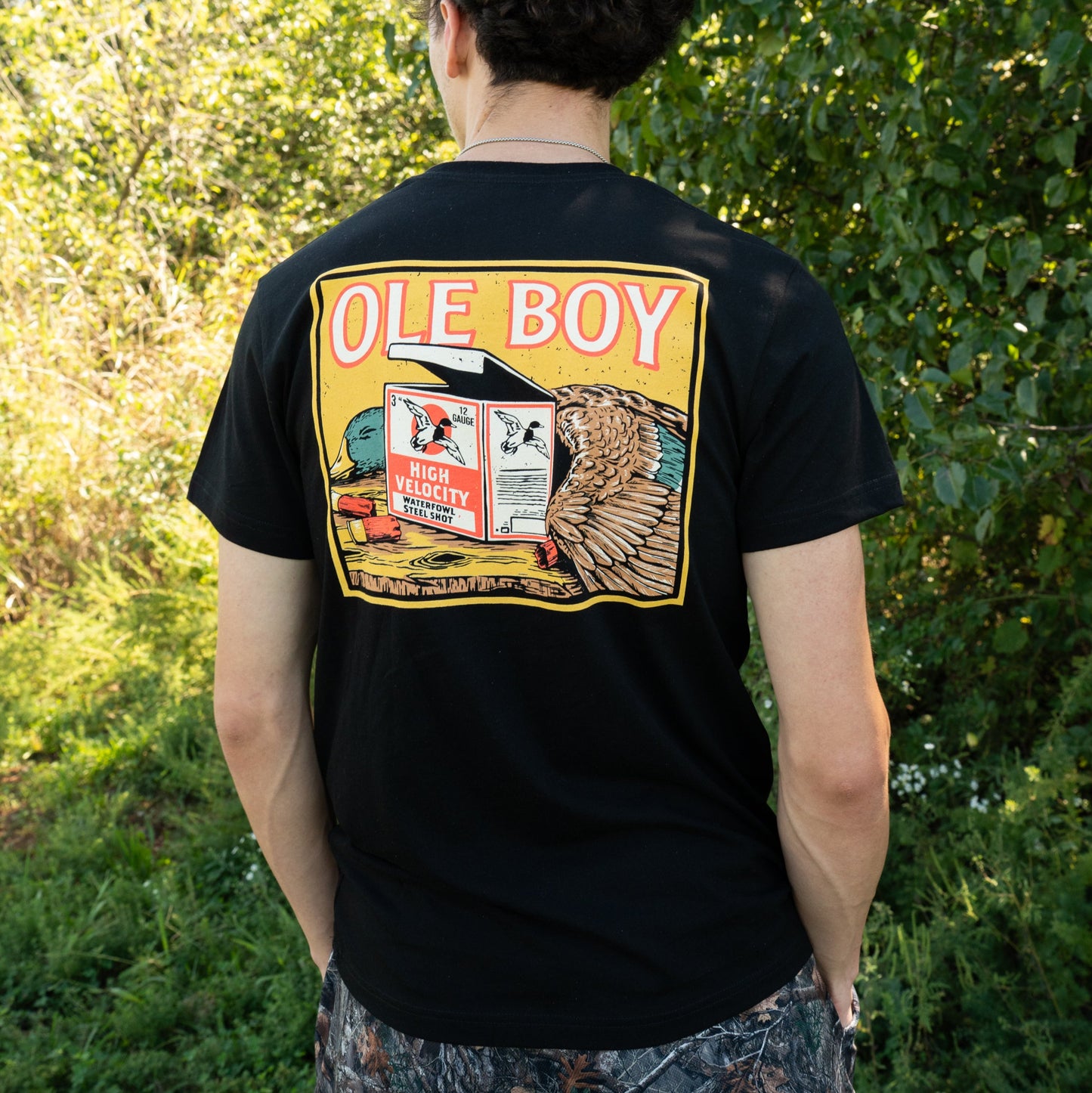 Person wearing a black t-shirt with 'Ole Boy' graphic design outdoors