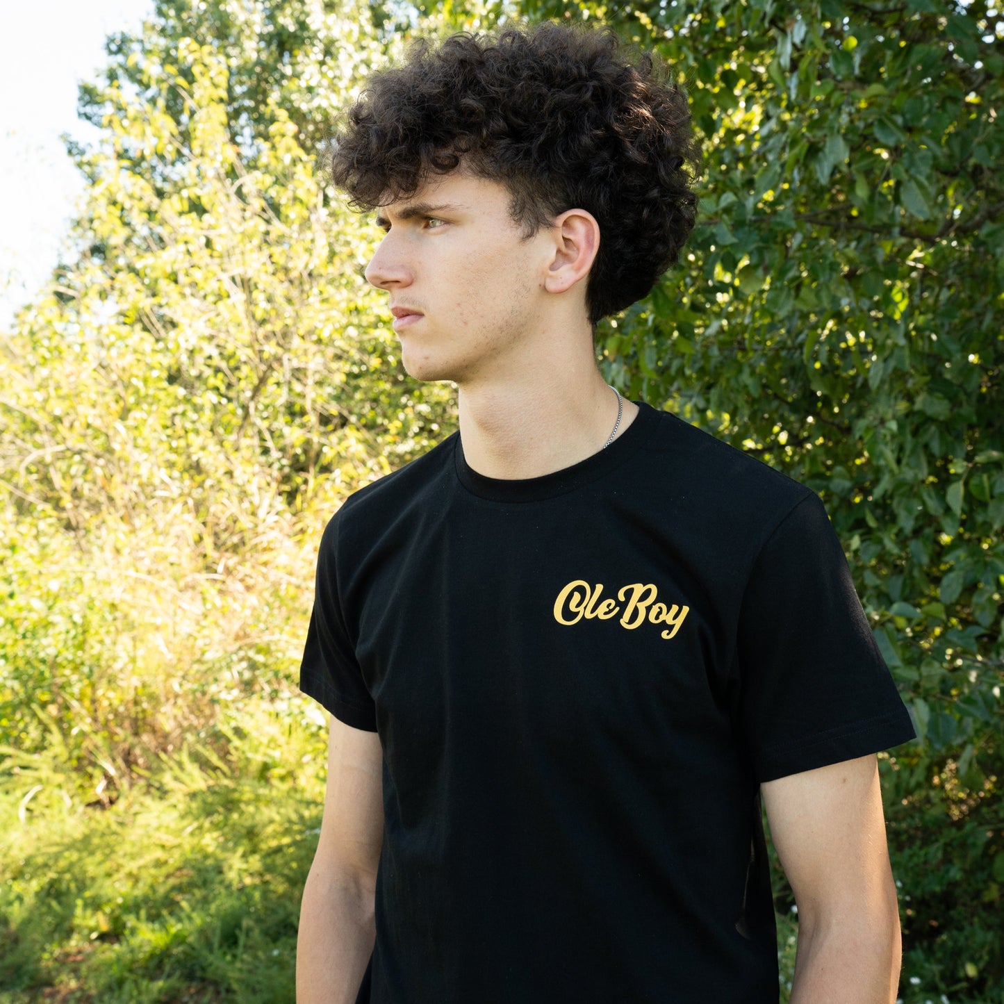Person wearing a black t-shirt with 'Ole Boy' text outdoors