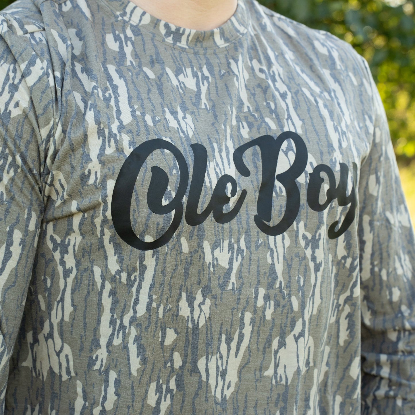 Camouflage-patterned shirt with 'Ole Boy' text on a blurred natural background