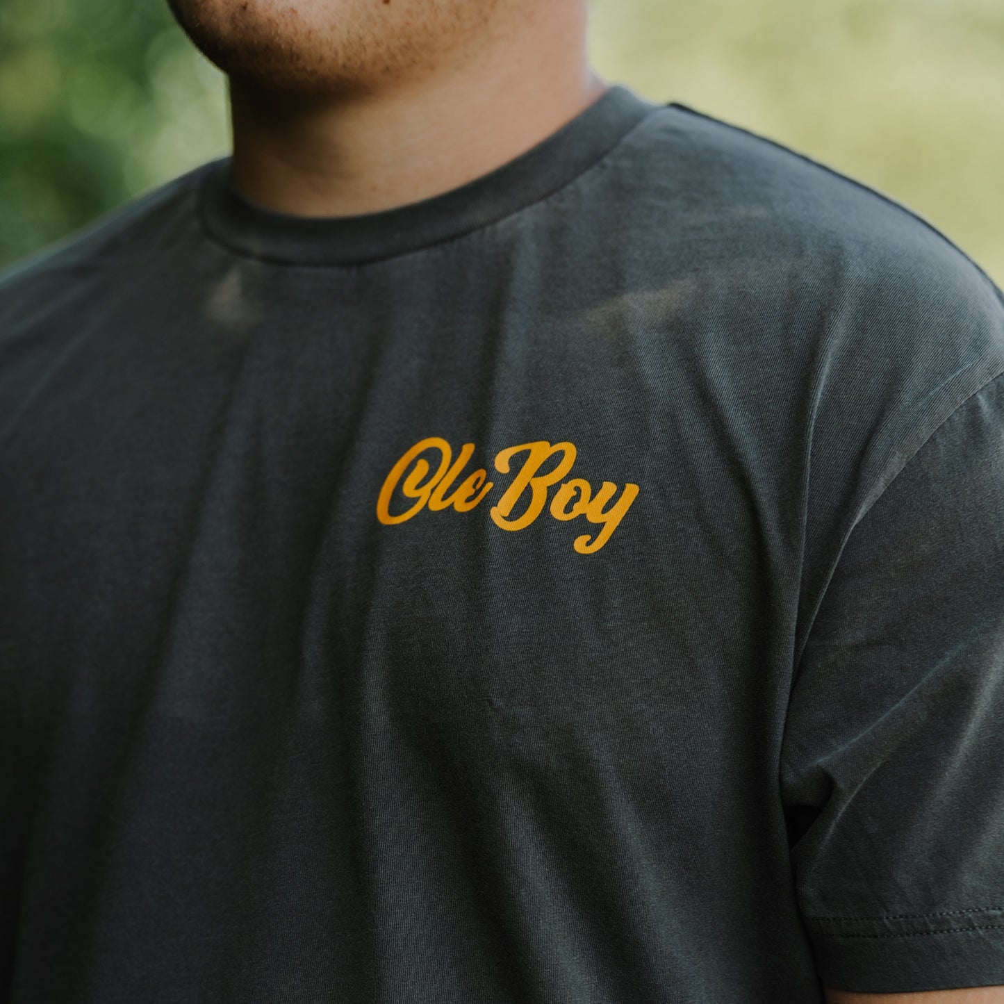 Person wearing a dark gray t-shirt with 'Ole Boy' printed in orange.