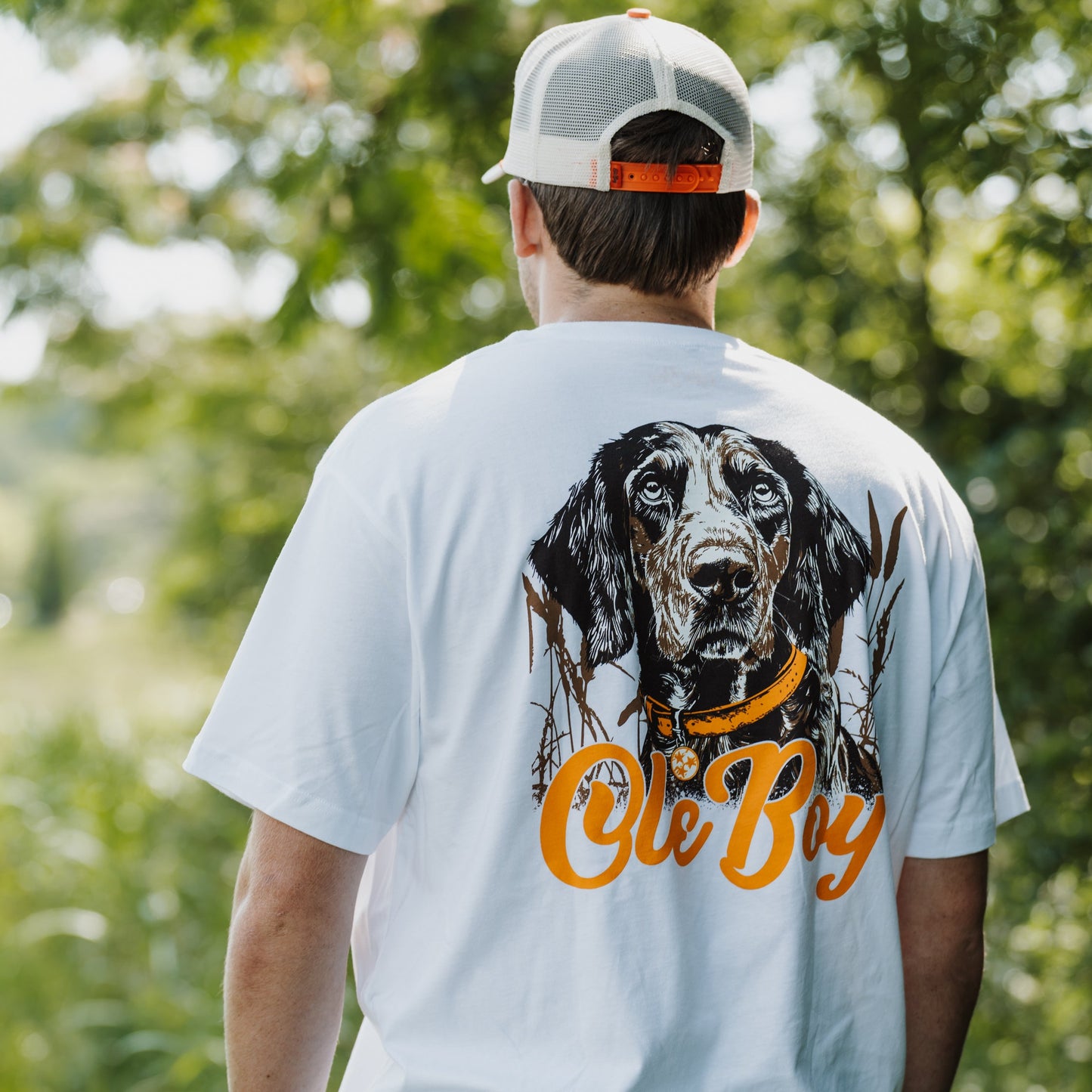 Person wearing a white t-shirt with a bluetick coonhound graphic and 'Ole Boy' text, standing outdoors.