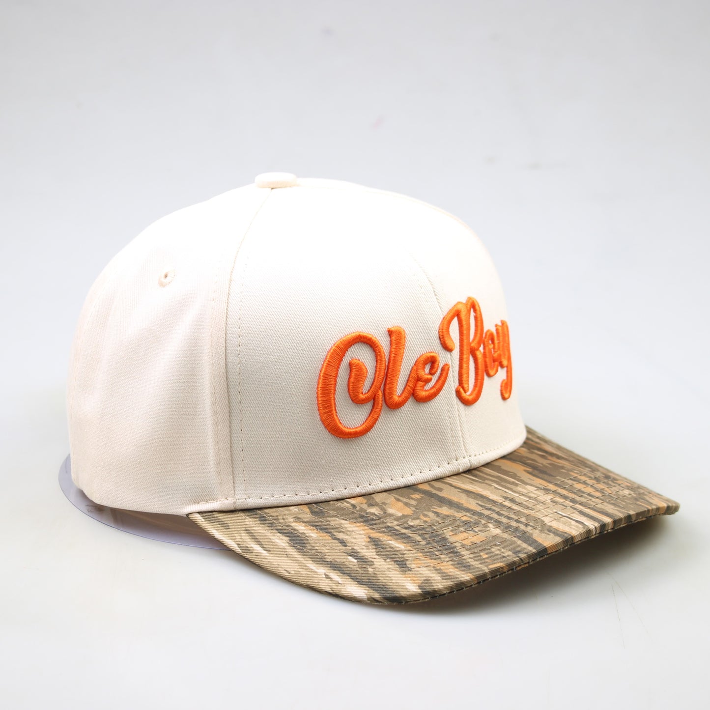 Beige cap with orange 'Ole Boy' text and wooden-patterned brim on a light gray background