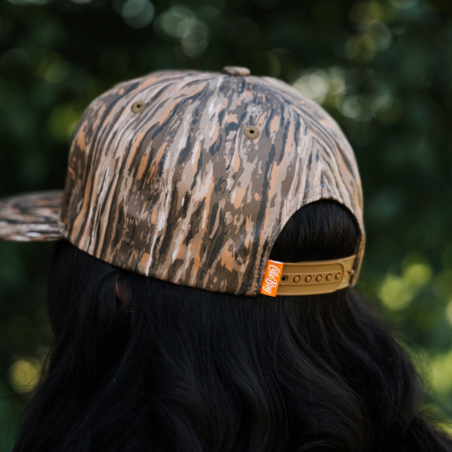 Person wearing a camouflage cap with a blurred green background