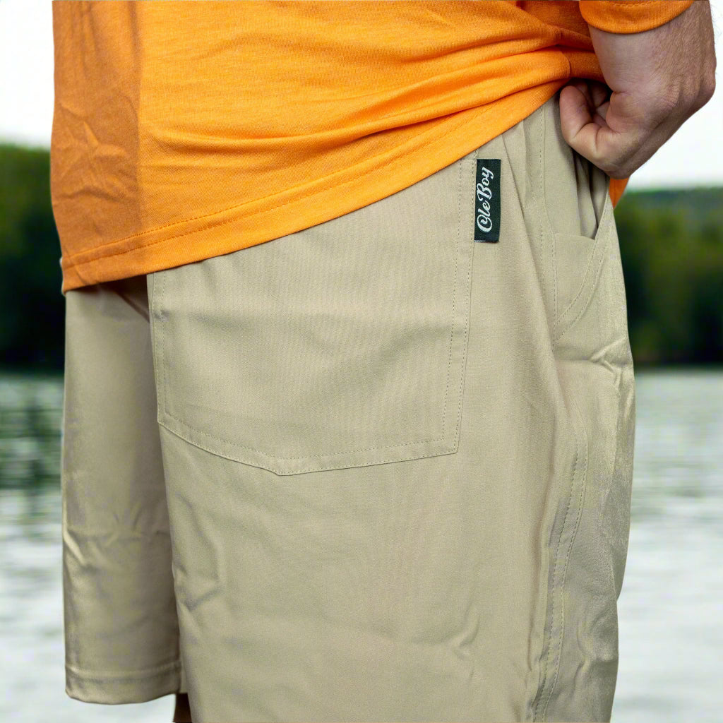 Person wearing khaki shorts with a visible brand logo on a white background