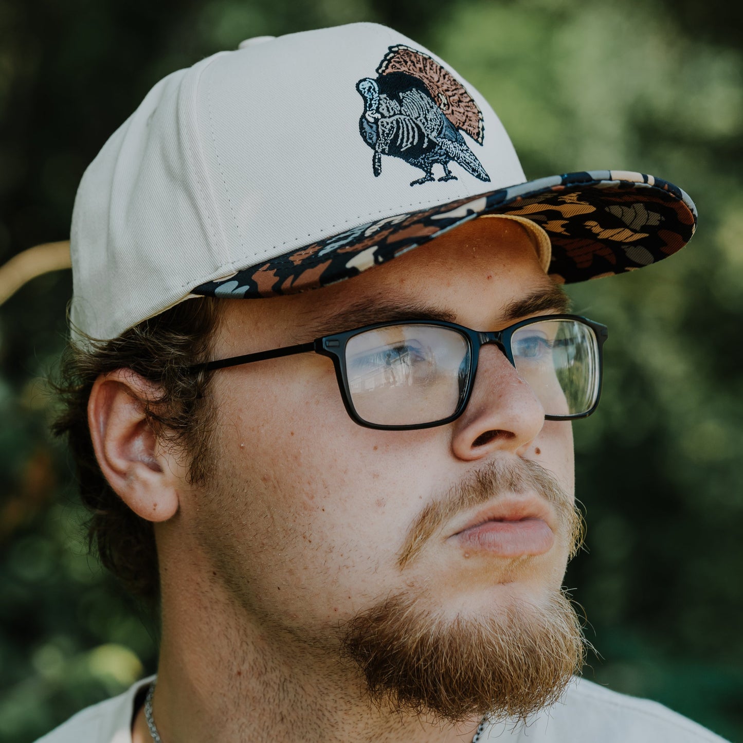 Man wearing a cap with a turkey design outdoors