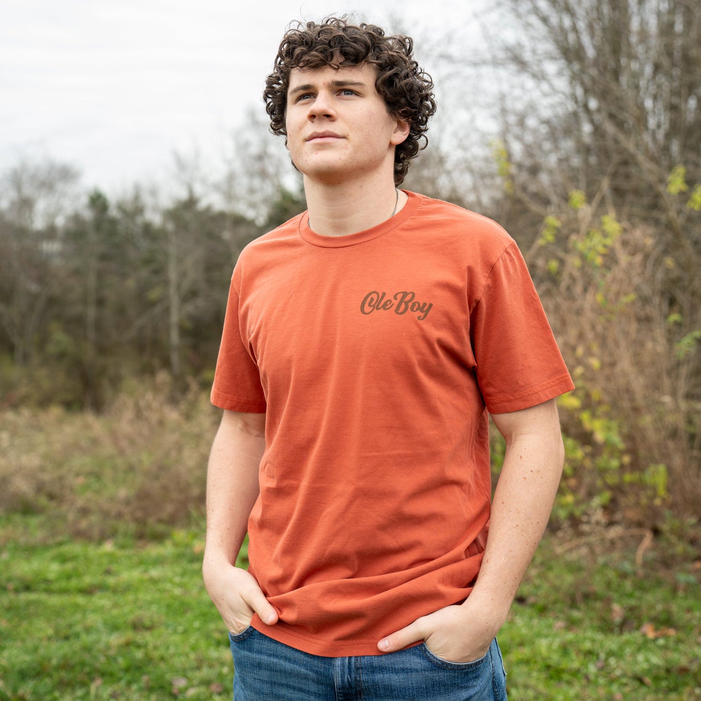 Person wearing an orange t-shirt with text in a natural setting