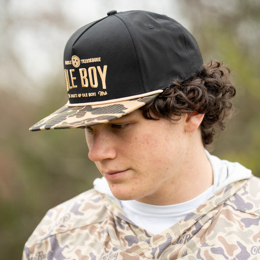 Person wearing a black cap with 'OLE BOY' branding outdoors