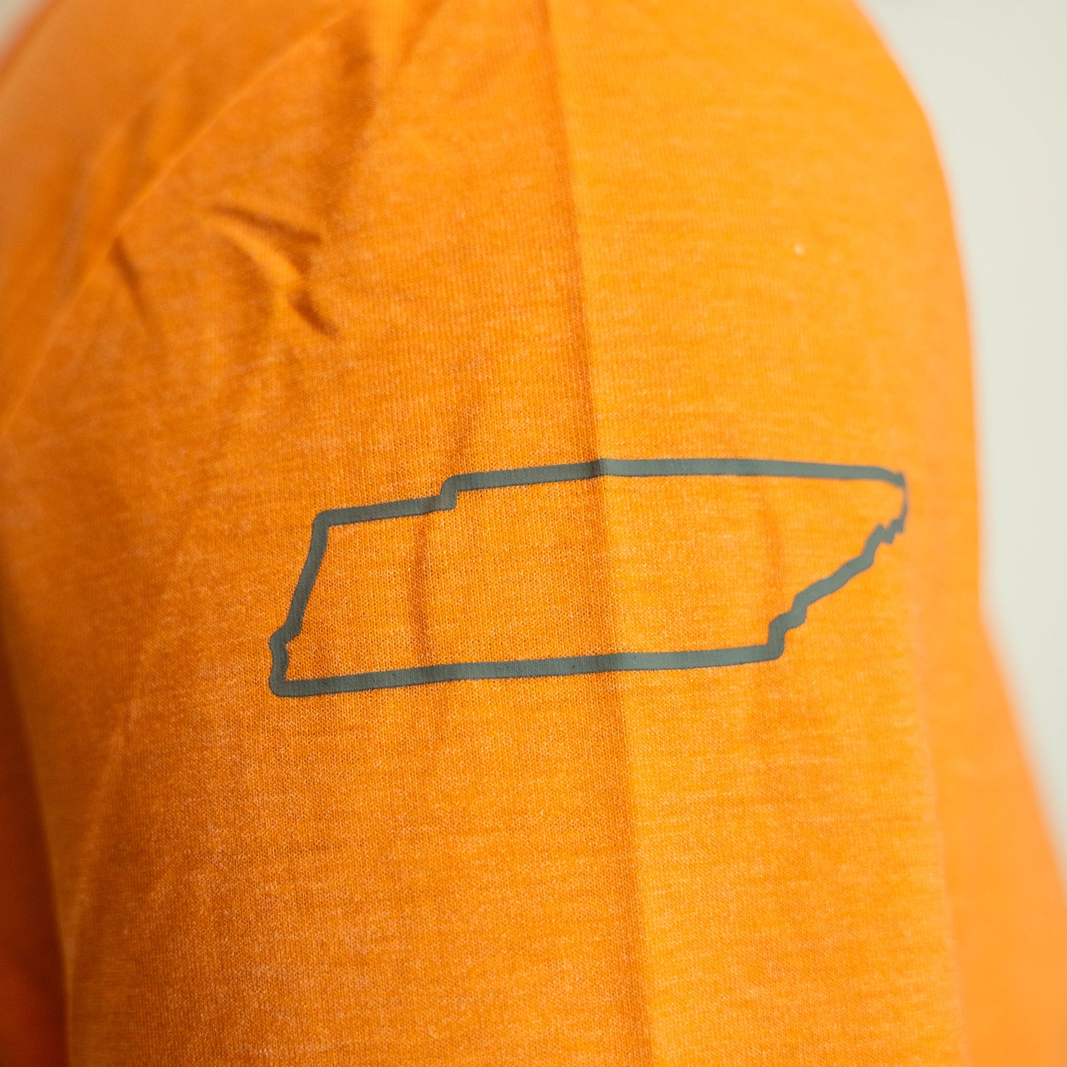 Orange shirt with a black outline of Tennessee on a white background