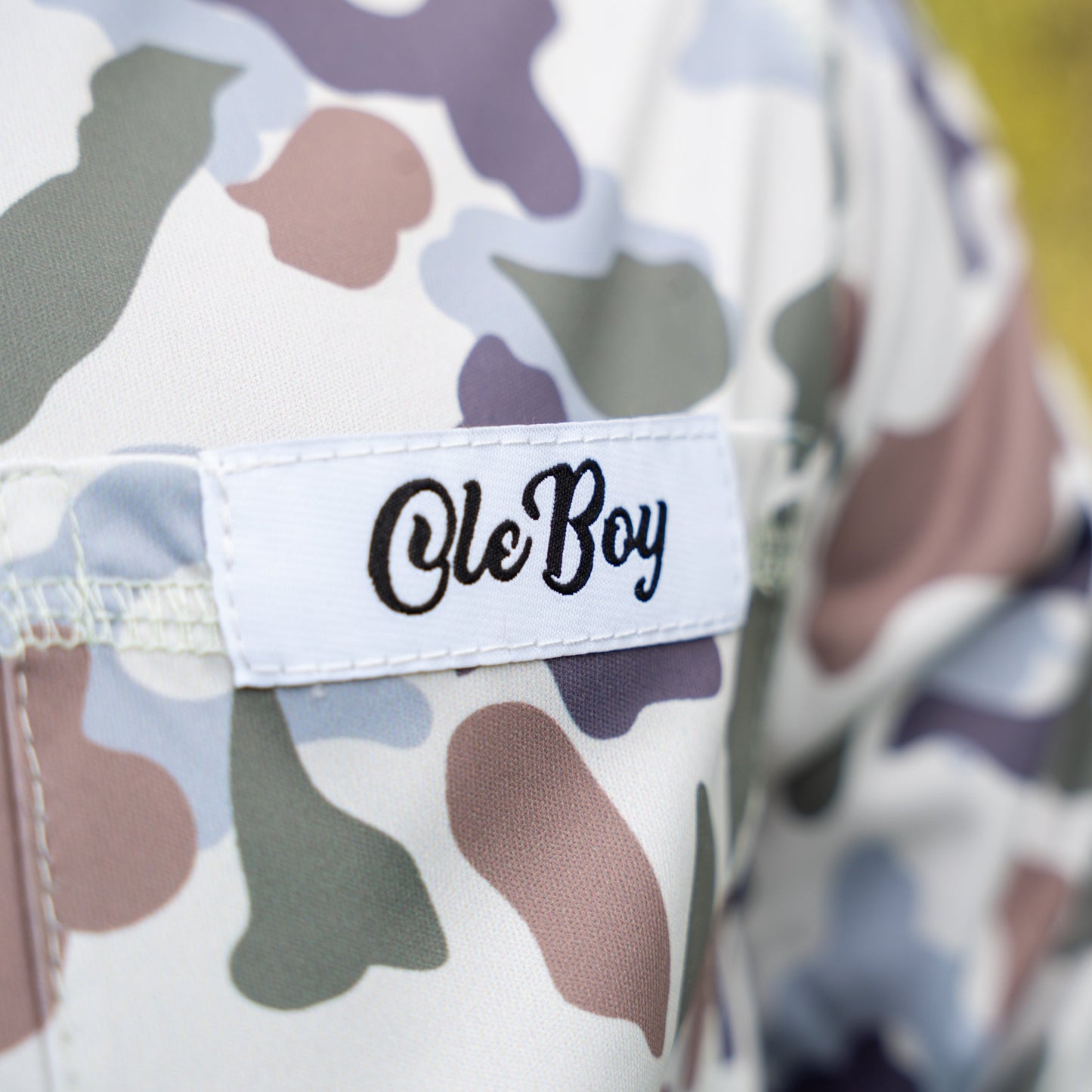 Camouflage-patterned pants with a 'Ole Boy' label on a blurred background