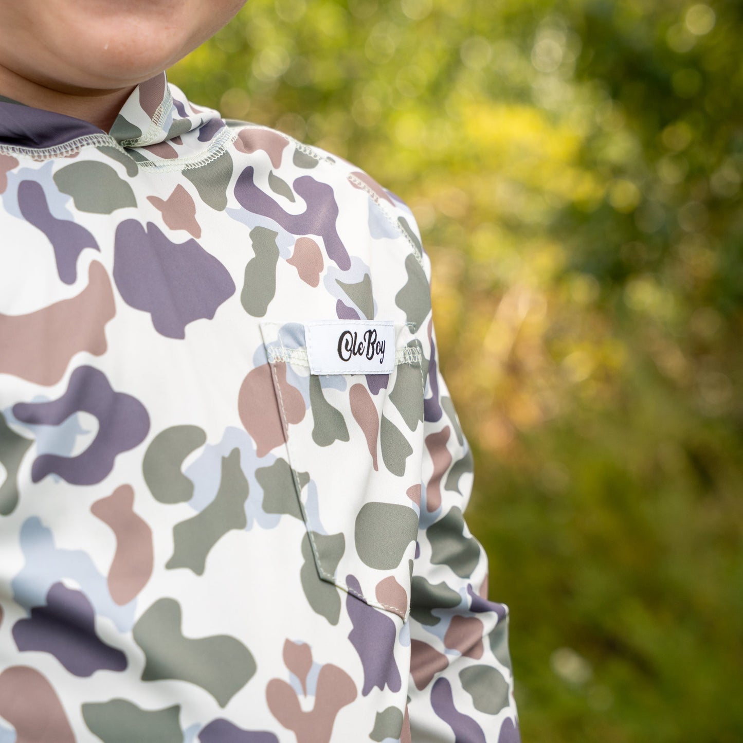 Person wearing a colorful patterned shirt with a brand logo outdoors.