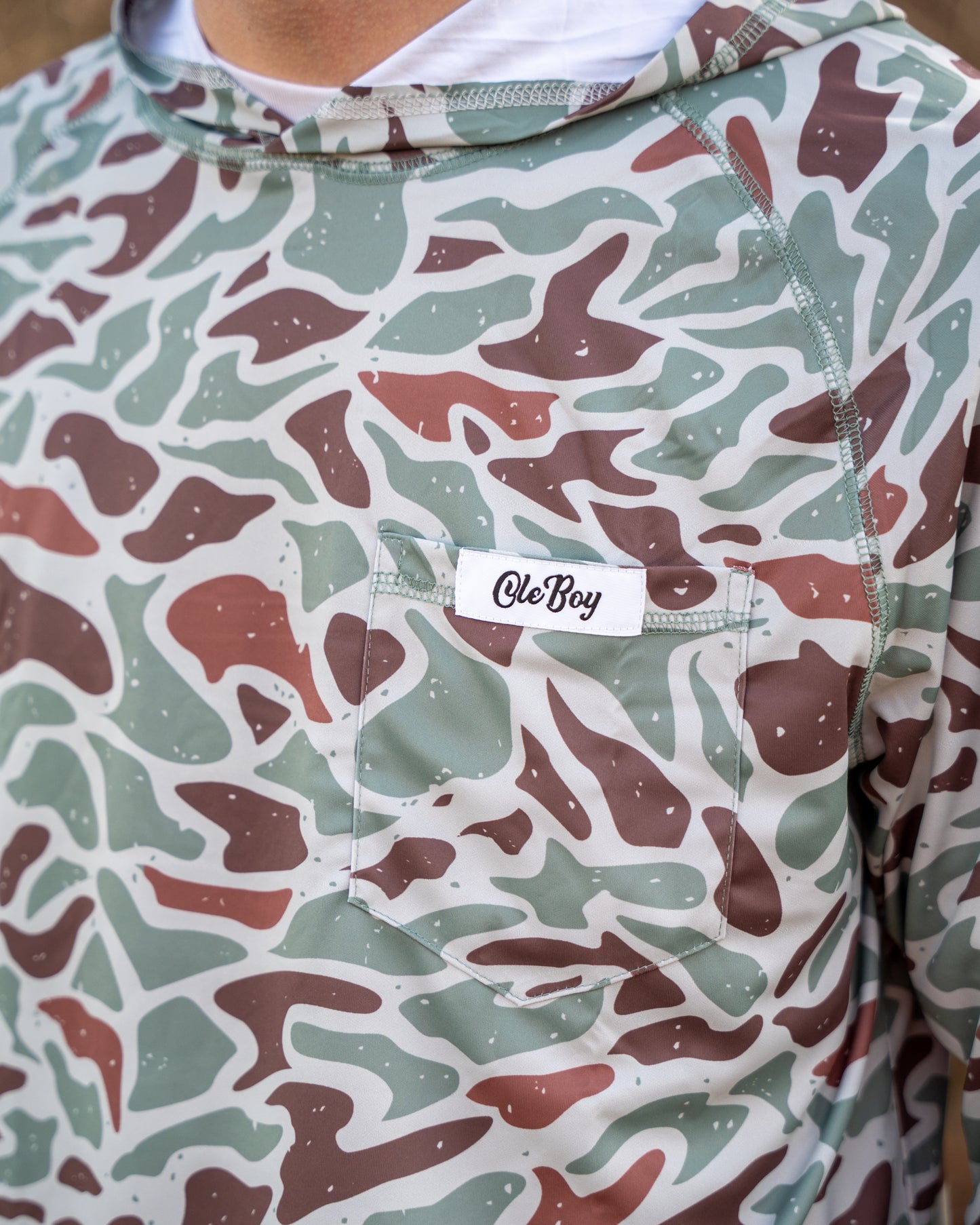 Camouflage-patterned hoodie with a visible brand label on a neutral background