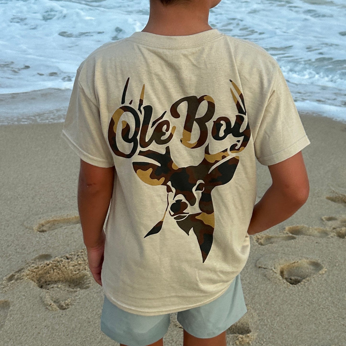 Child wearing a Ole Boy t-shirt with Deer design on a sandy beach