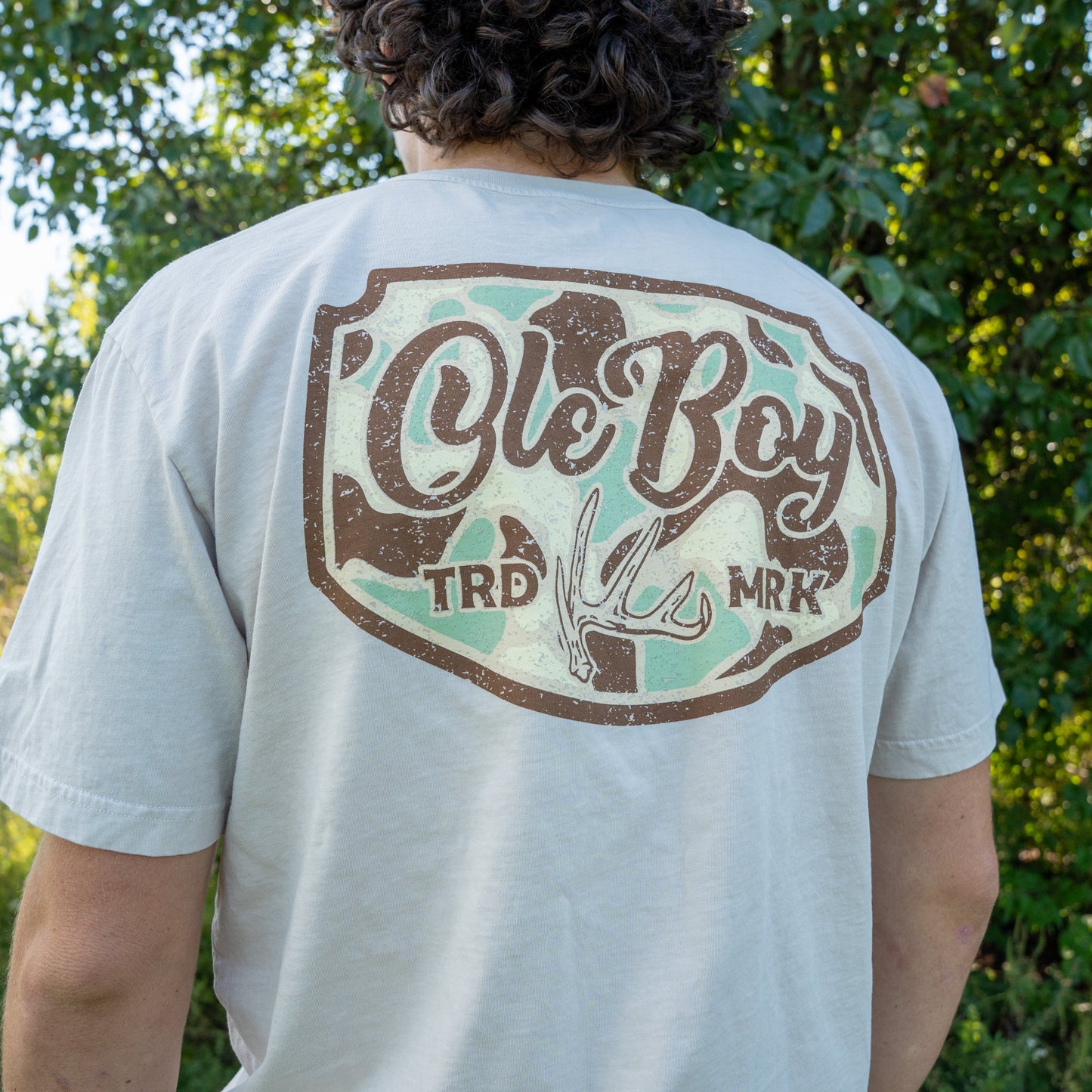 Person wearing a white t-shirt with 'Ole Boy' logo outdoors