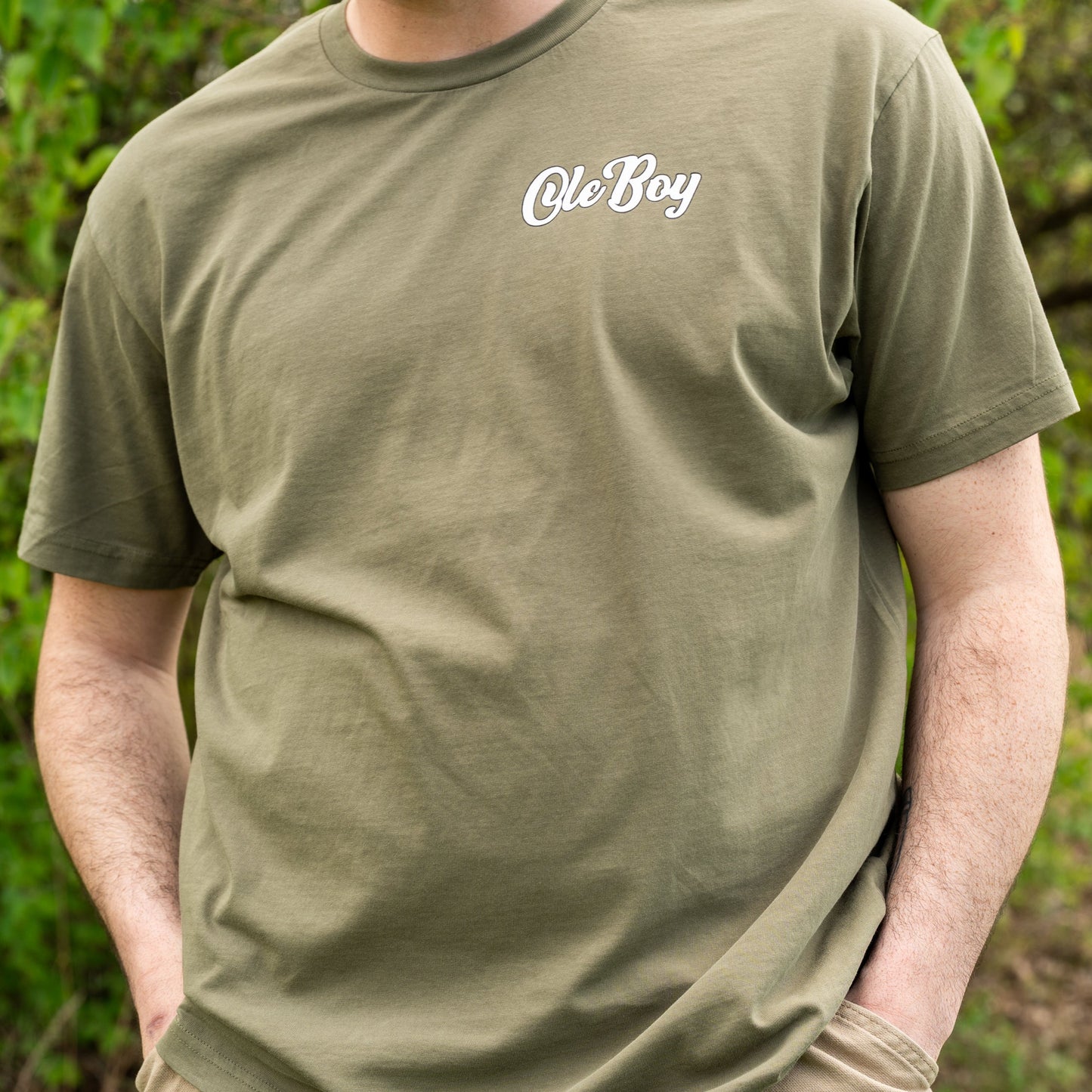 Person wearing a green t-shirt with 'Ole Boy' text in a natural setting