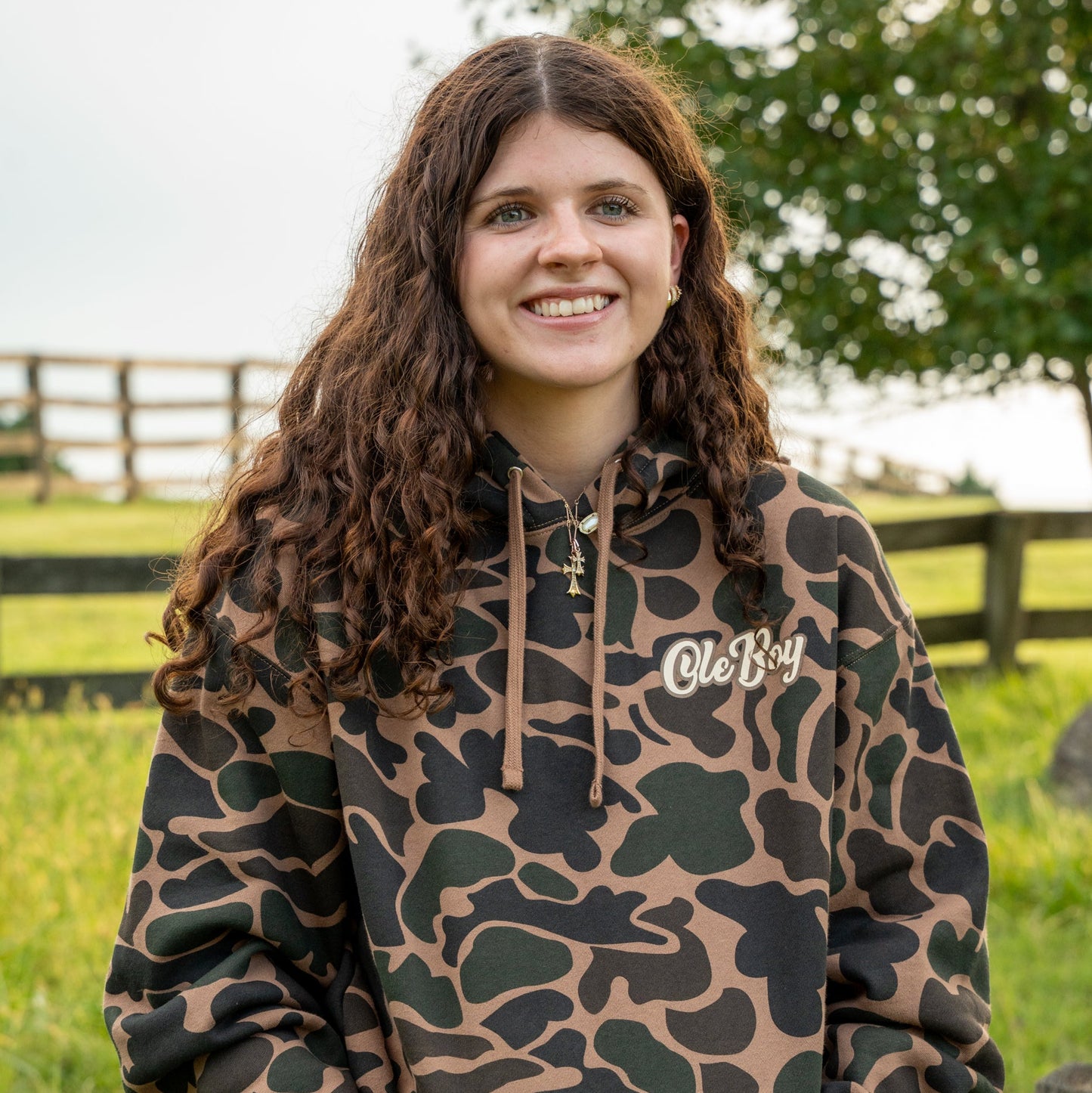 Person wearing a camouflage hoodie with 'Ole Boy' logo in an outdoor setting