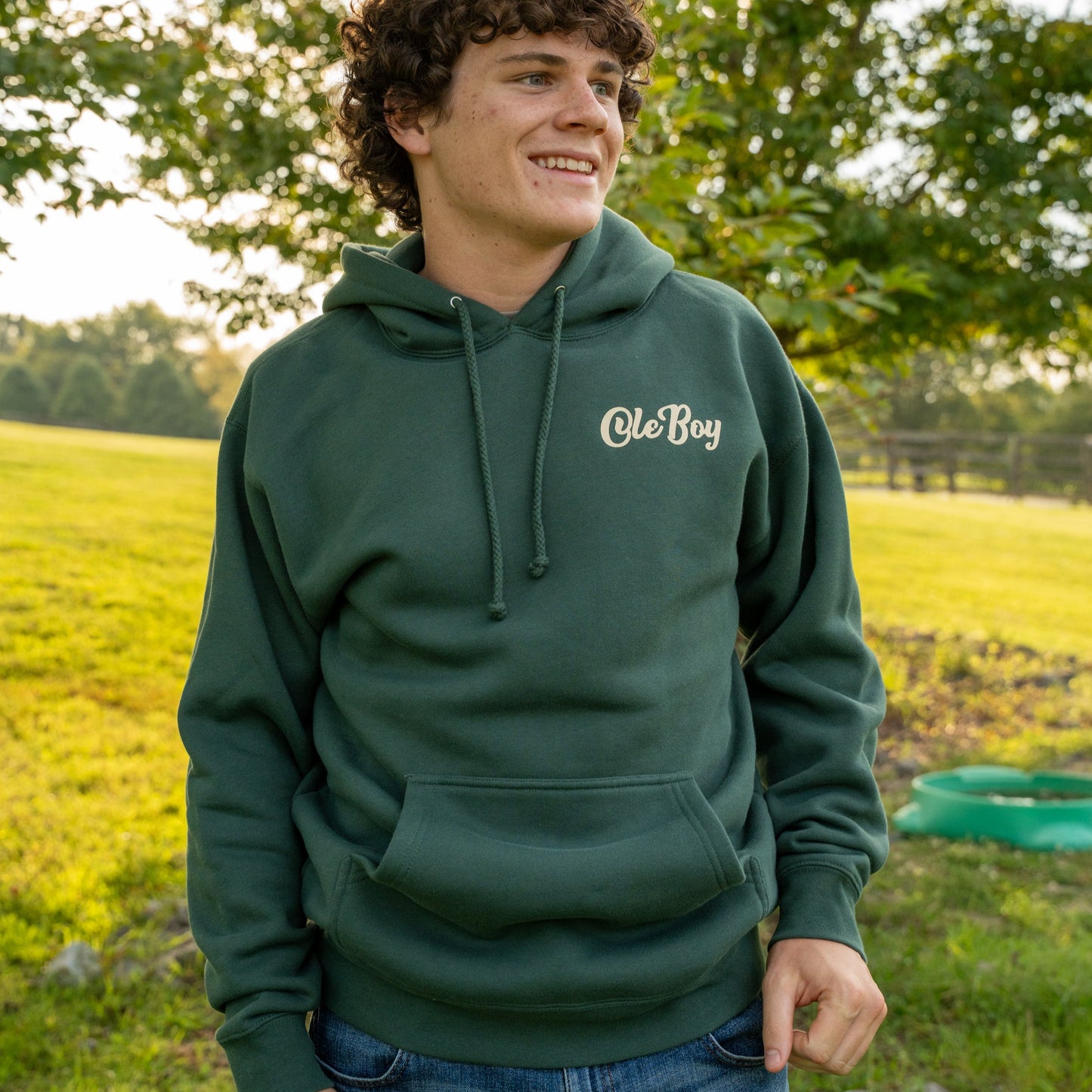 Person wearing a green hoodie with 'Ole Boy' logo in a grassy field