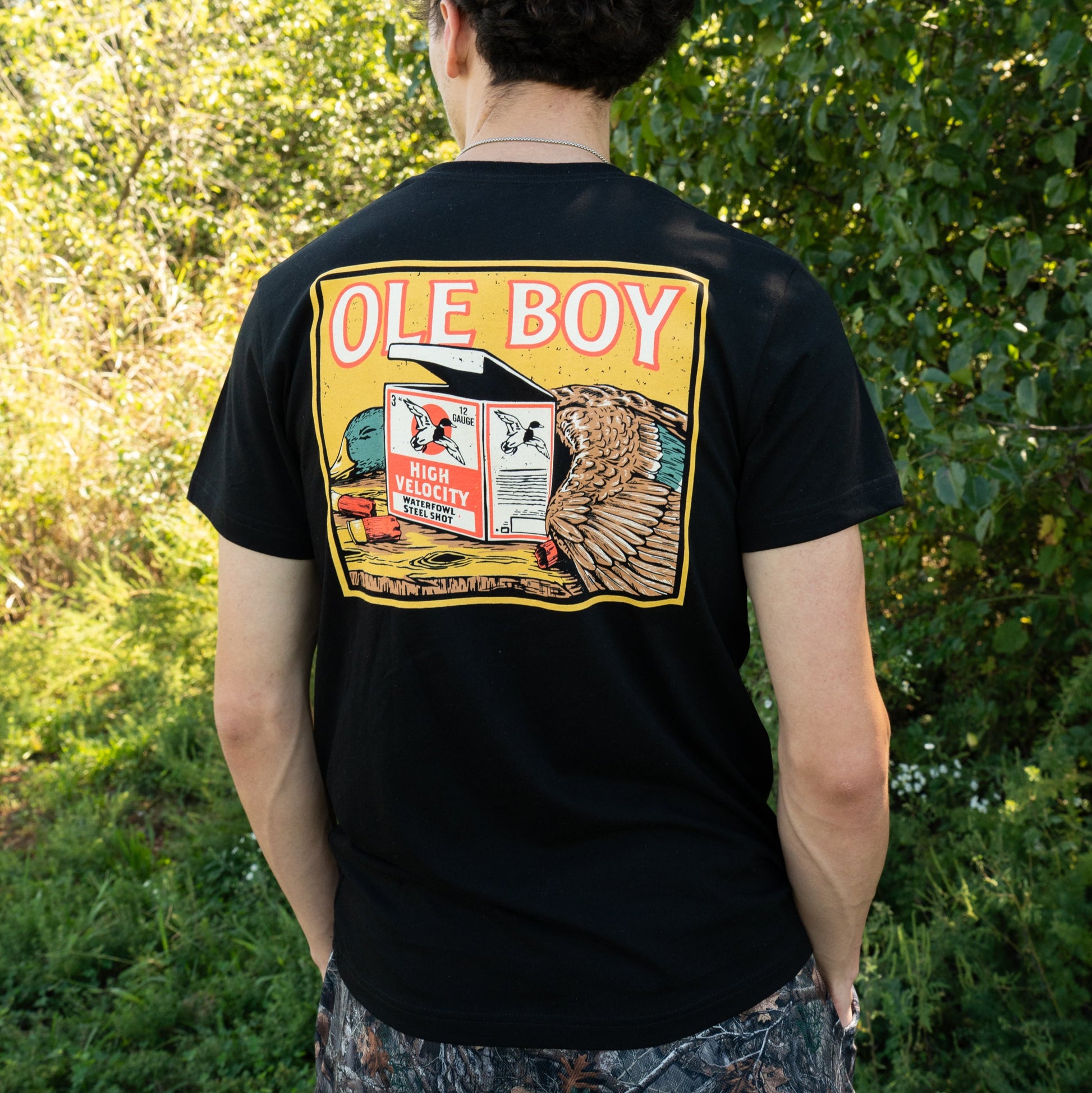 Person wearing a black t-shirt with 'Ole Boy' graphic design outdoors