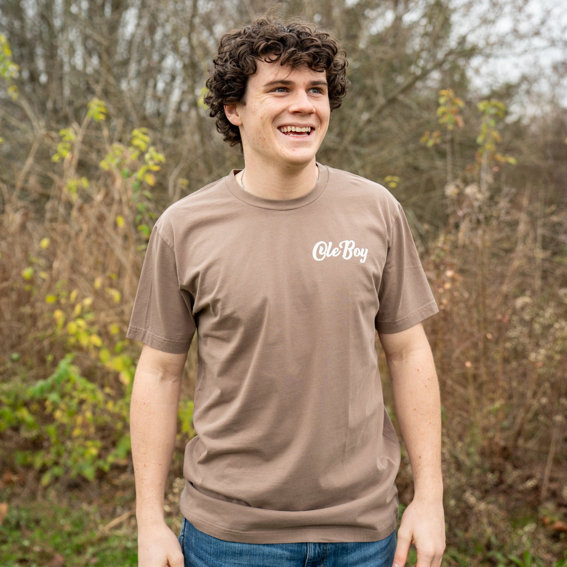Person wearing a brown t-shirt with 'Ole Boy' logo outdoors