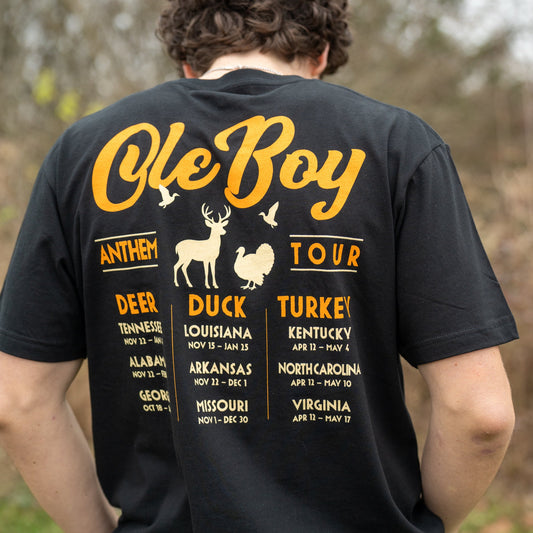 Person wearing a black t-shirt with 'Ole Boy' and tour details on the back, outdoors.
