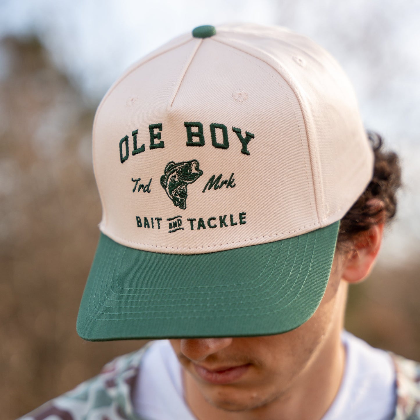 Beige and green cap with 'Ole Boy' branding worn by a person outdoors.