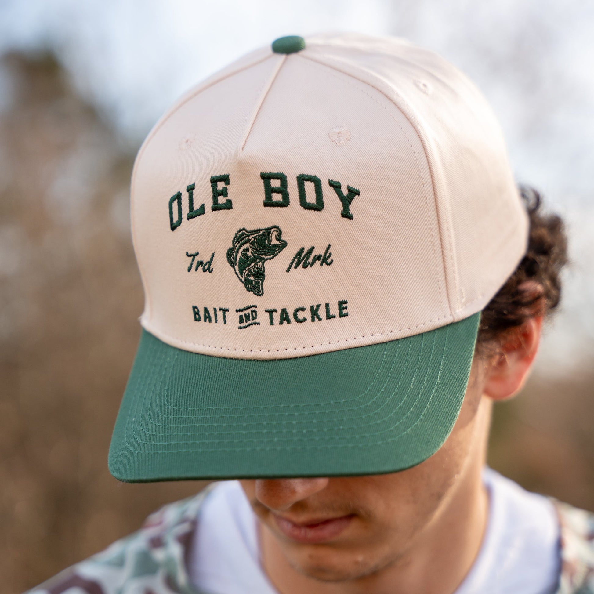 Beige and green cap with 'Ole Boy' branding worn by a person outdoors.