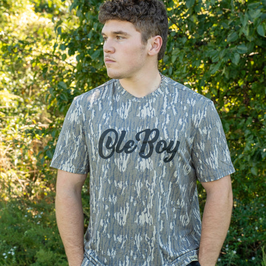 Person wearing a camouflage t-shirt with 'Ole Boy' text outdoors.