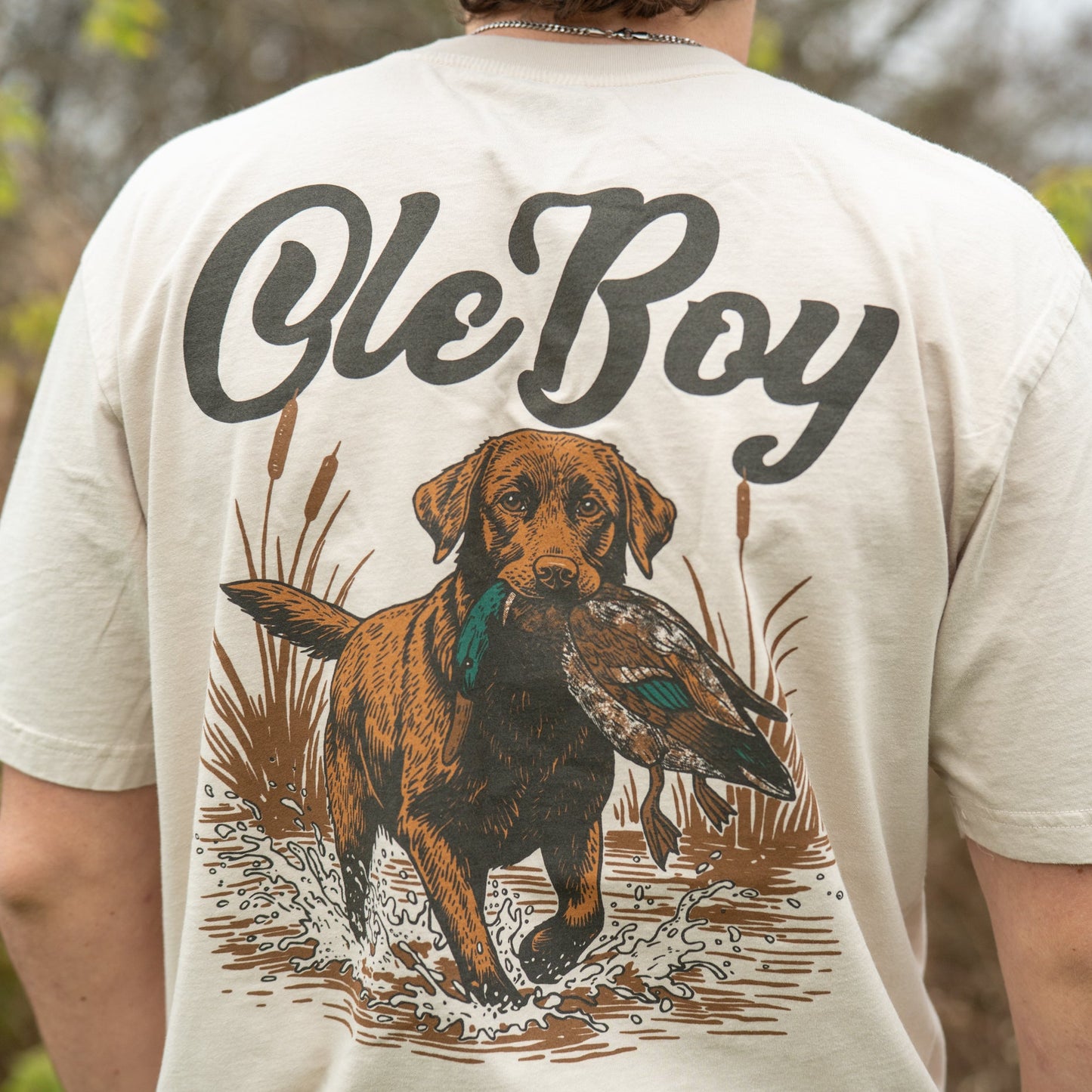 Person wearing a t-shirt with a dog graphic and 'Ole Boy' text in an outdoor setting