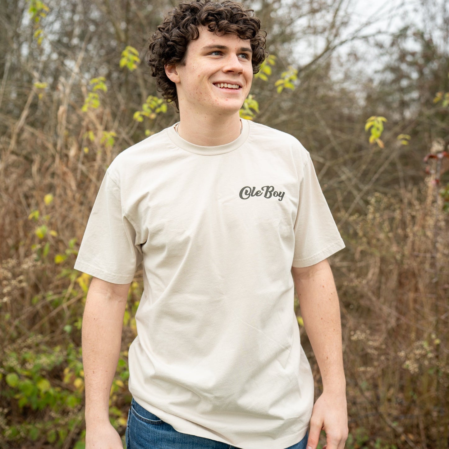 Person wearing a white t-shirt with a logo in a forest setting