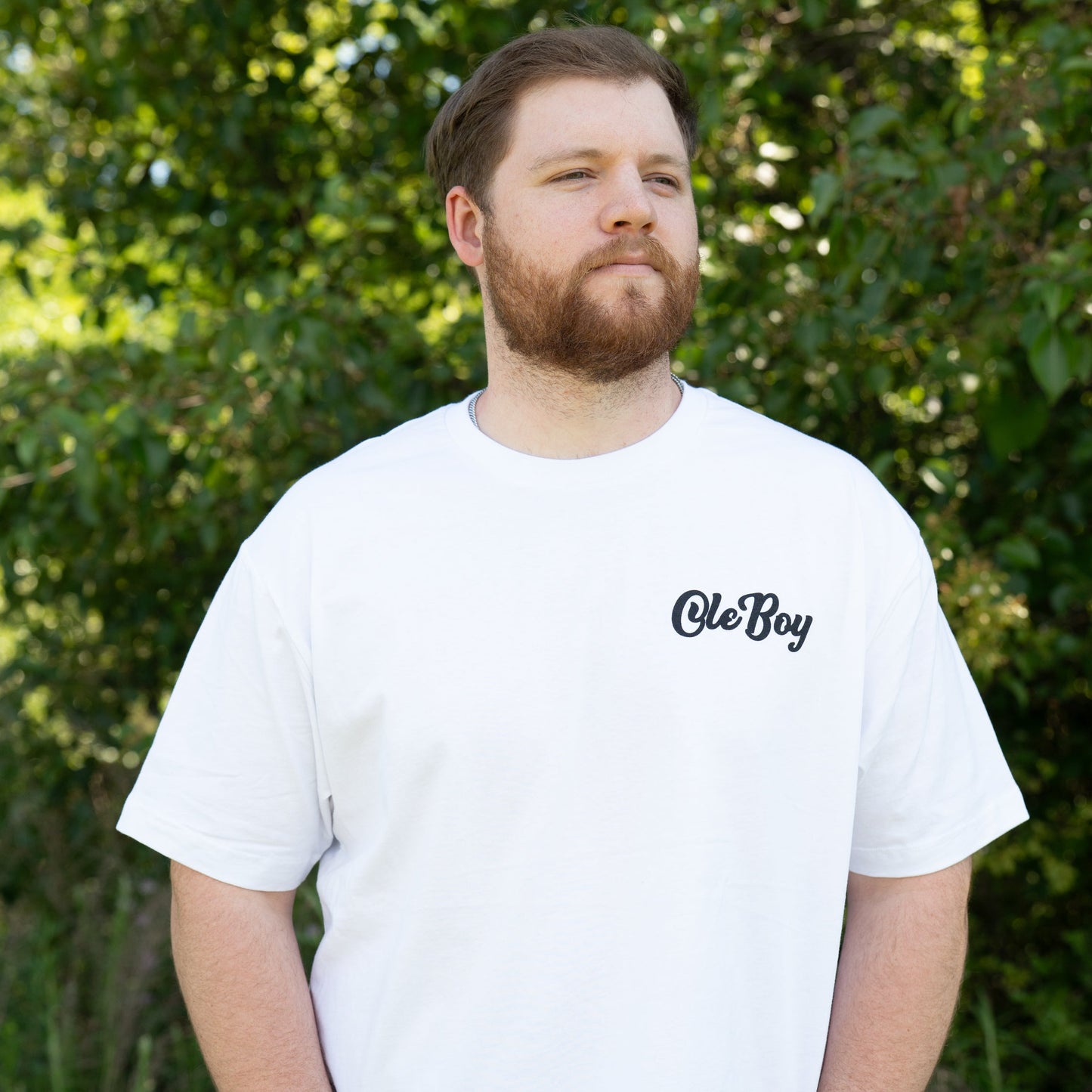 Man wearing a white t-shirt with 'Ole Boy' logo outdoors