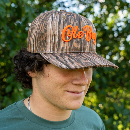 Person wearing a camouflage cap with 'Ole Boy' text outdoors