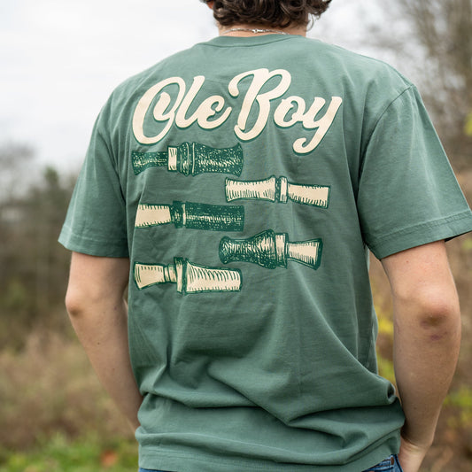 Person wearing a green t-shirt with 'Ole Boy' text and graphics outdoors.