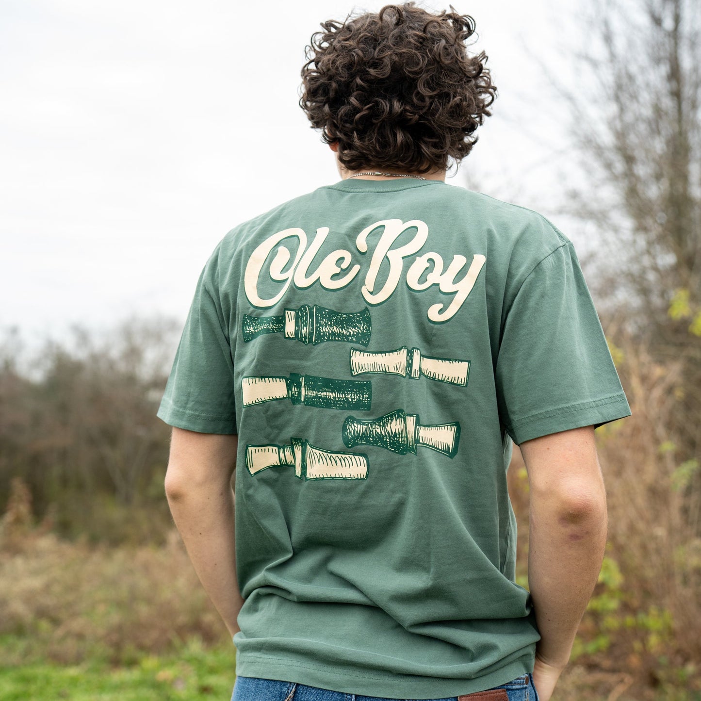 Person wearing a green t-shirt with 'ole Boy' text outdoors