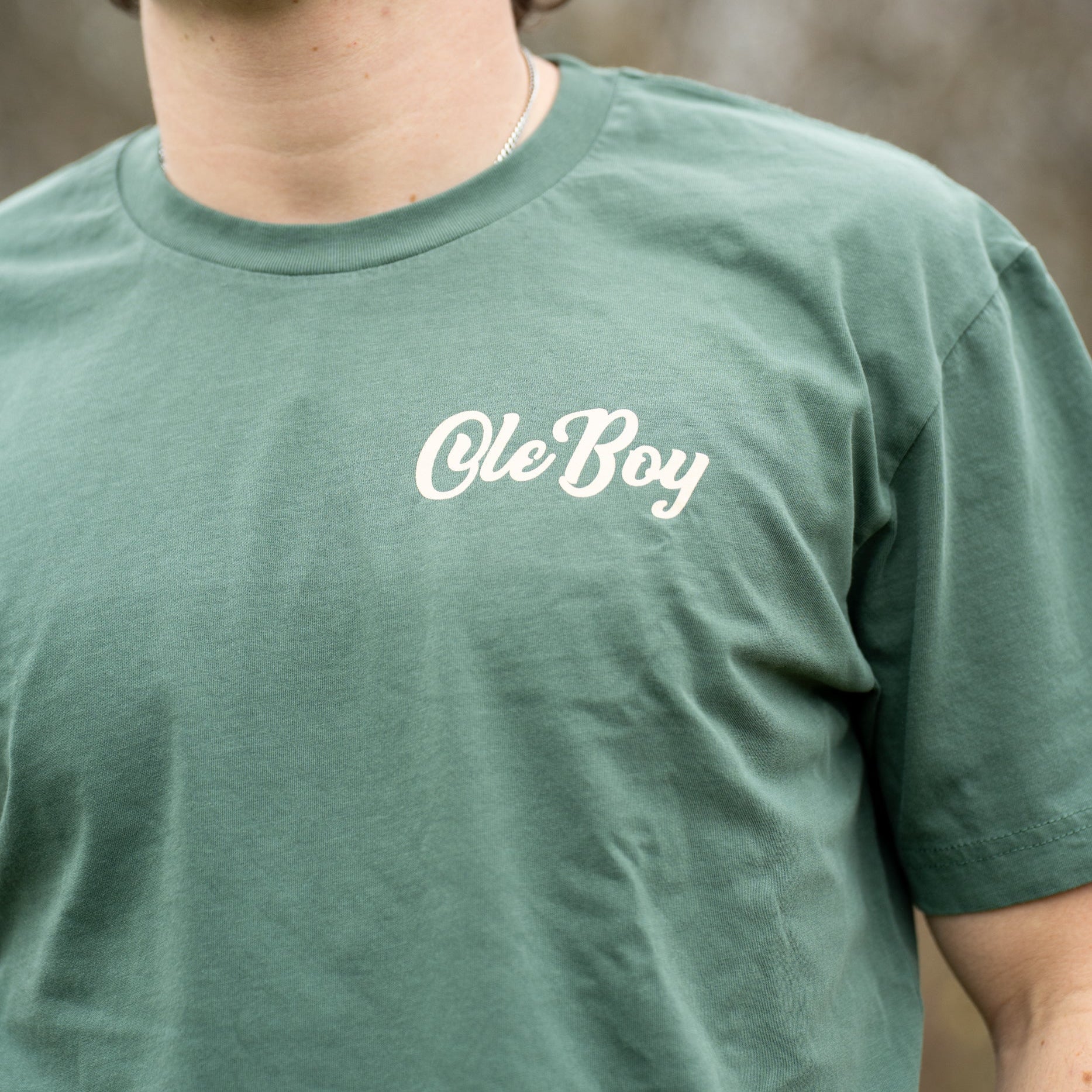 Person wearing a green t-shirt with 'Ole Boy' text outdoors