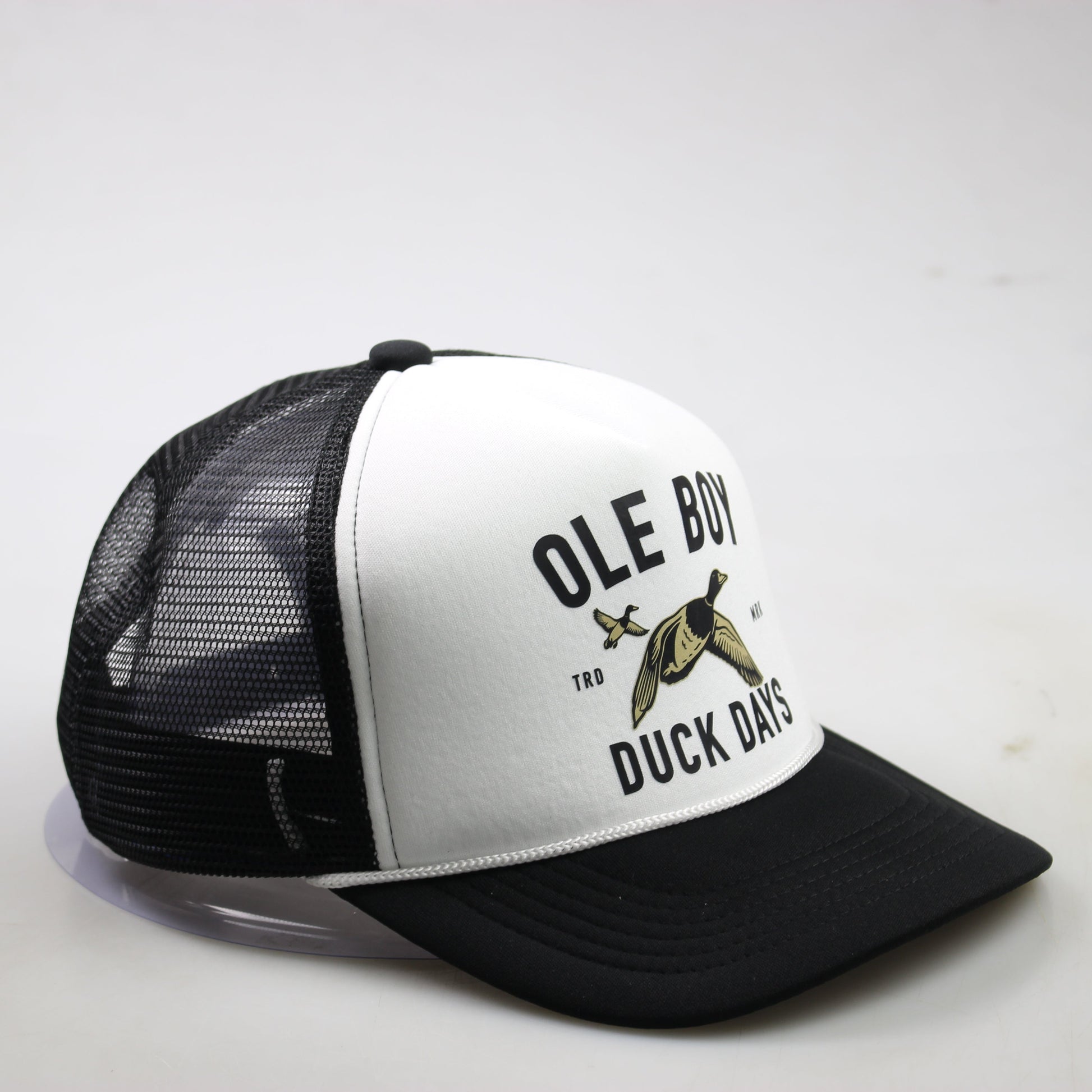 Black and white trucker hat with duck graphic and text on a light gray background