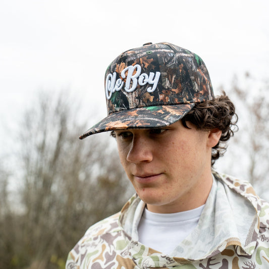 Person wearing a camouflage cap with 'Ole Boy' text outdoors