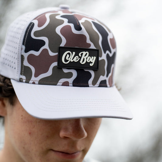 Person wearing a camouflage and white trucker cap with 'Ole Boy' logo.