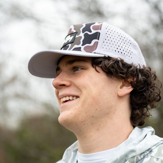 Person wearing a camouflage baseball cap with a blurred natural background