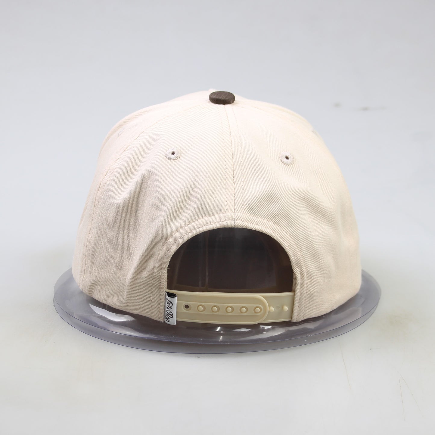 Beige baseball cap with a clear display case on a light gray background