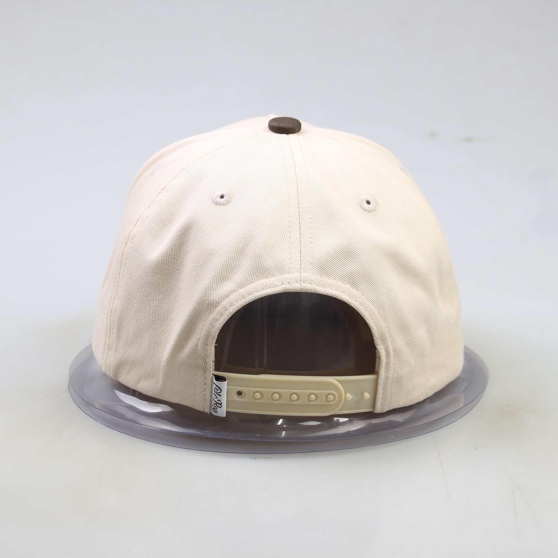 Beige baseball cap with a clear display case on a light gray background