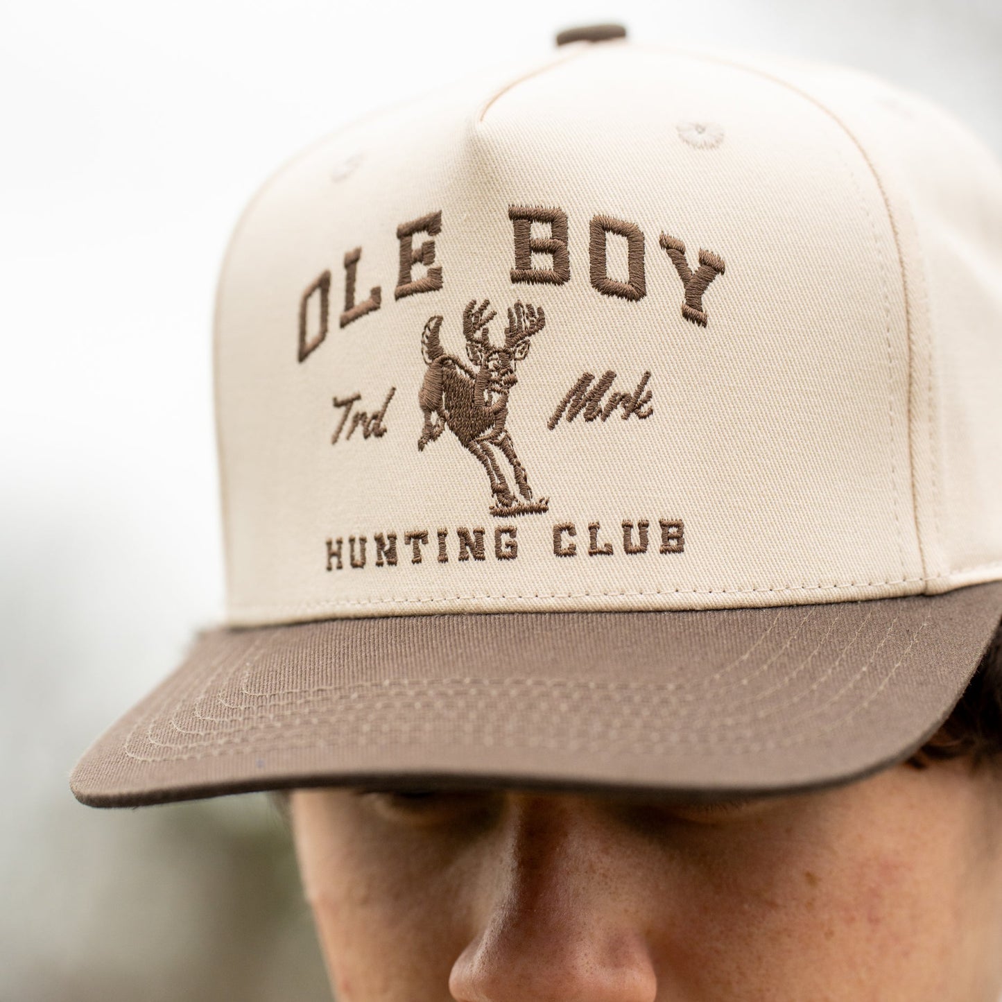 Beige cap with 'Ole Boy Hunting Club' text and logo worn by a person.