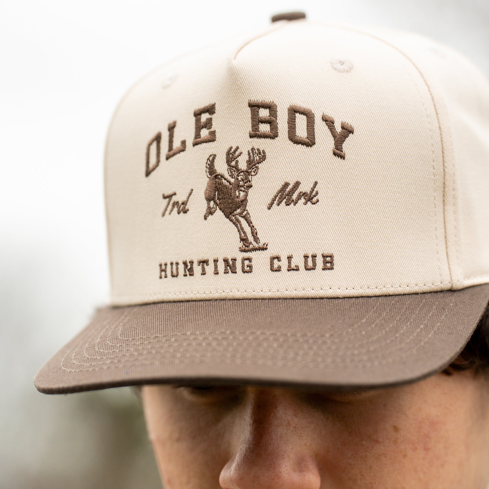Beige cap with 'Ole Boy Hunting Club' text and logo worn by a person.