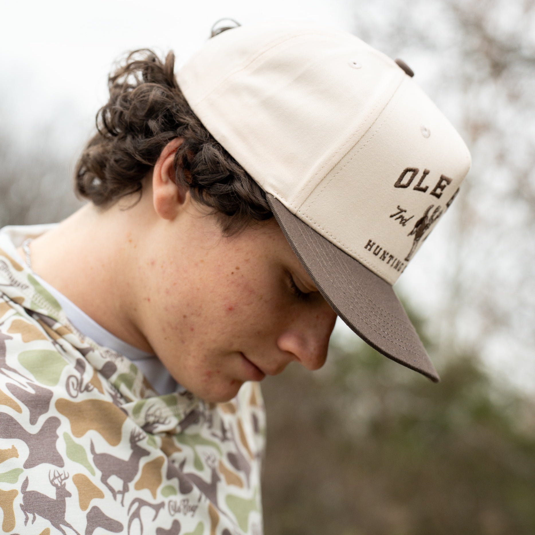 Person wearing a beige cap with 'Ole Boy' branding, outdoors.