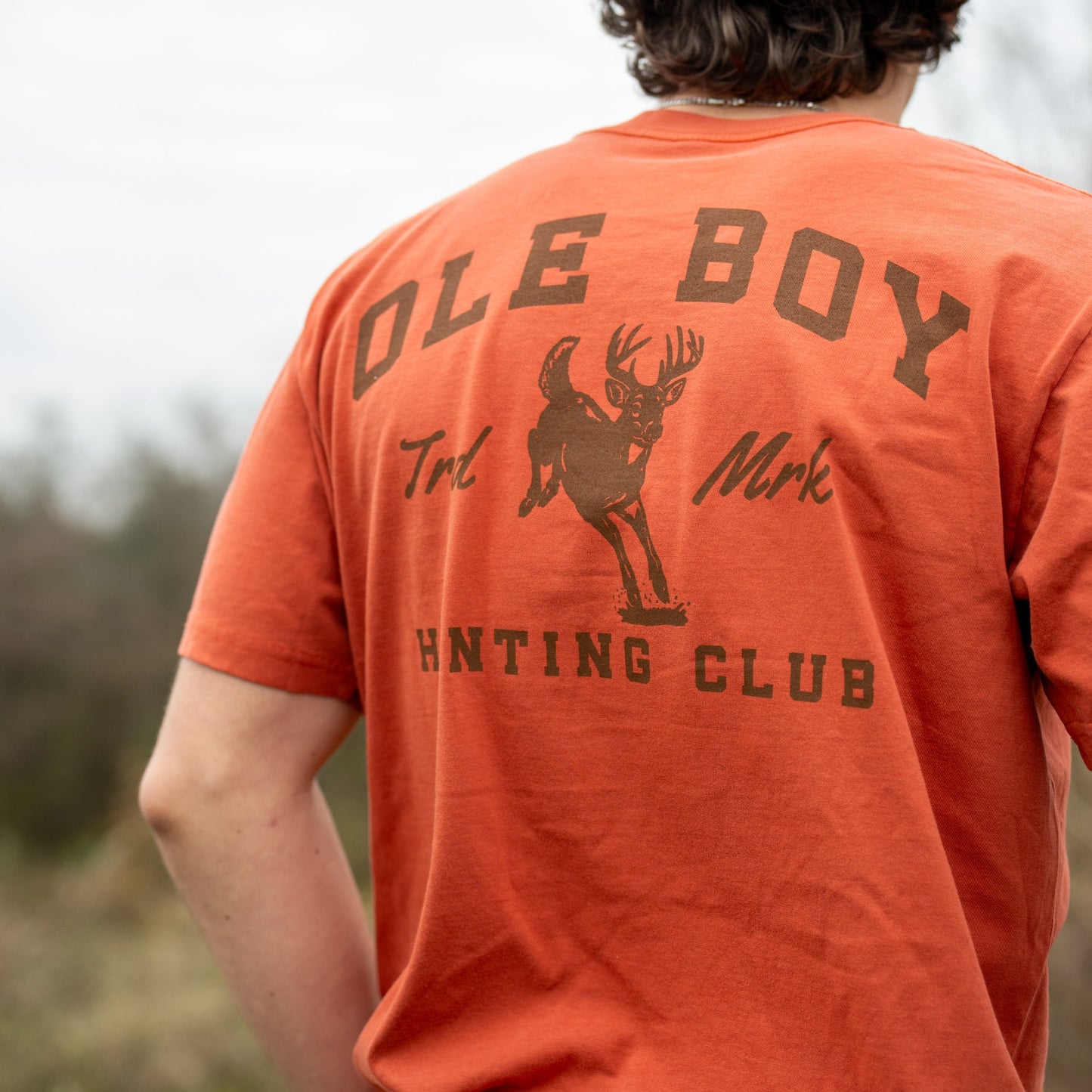 Person wearing an orange t-shirt with 'Ole Boy Hunting Club' text and deer graphic.