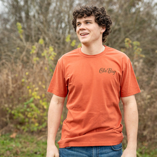 Person wearing an orange t-shirt with a logo outdoors