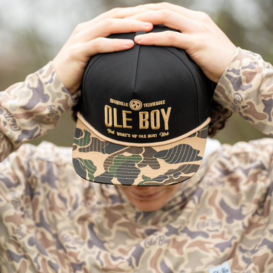Person holding a black and camouflage ball with 'Ole Boy' branding.
