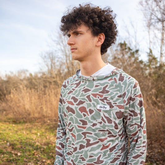 Person wearing a camouflage hoodie in an outdoor setting