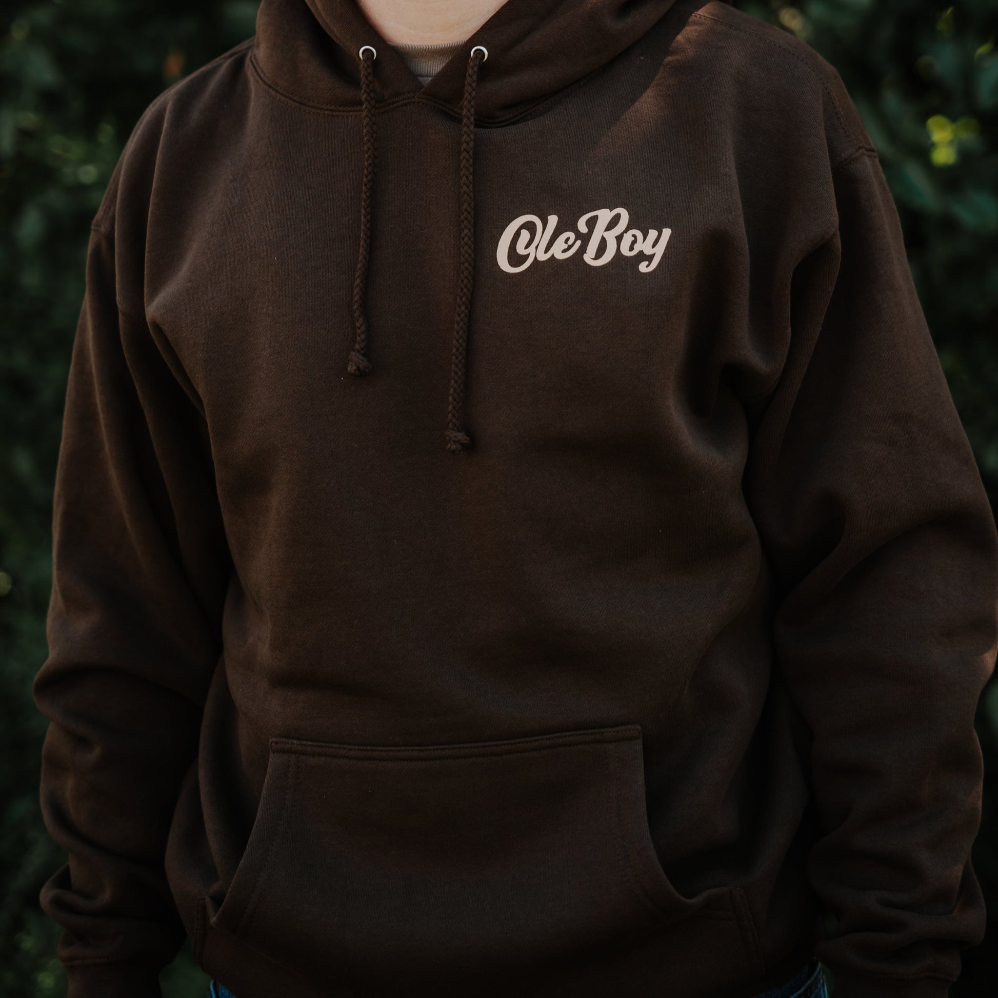 Person wearing a brown hoodie with 'Ole Boy' text against a dark background