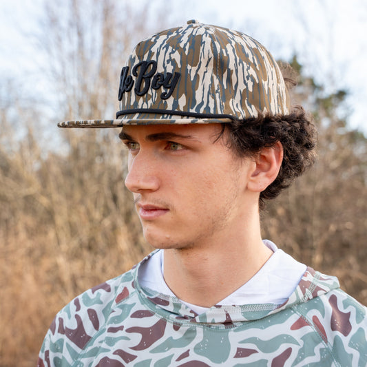 Person wearing a camouflage cap and hoodie outdoors