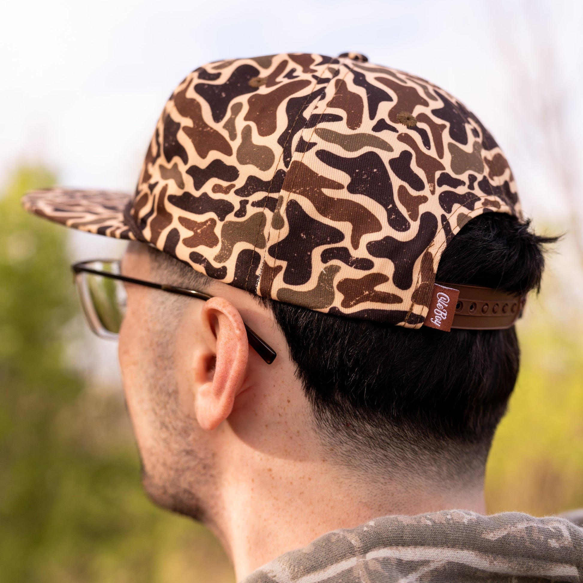 Person wearing a camouflage cap with a blurred natural background