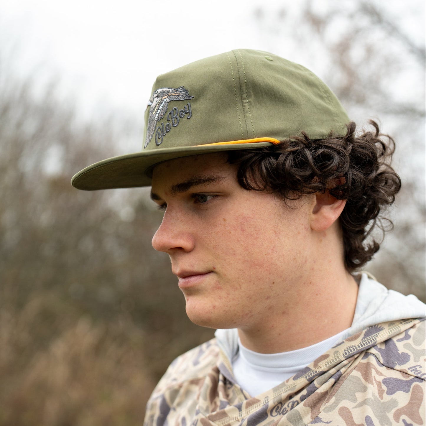 Person wearing a green cap with a logo outdoors